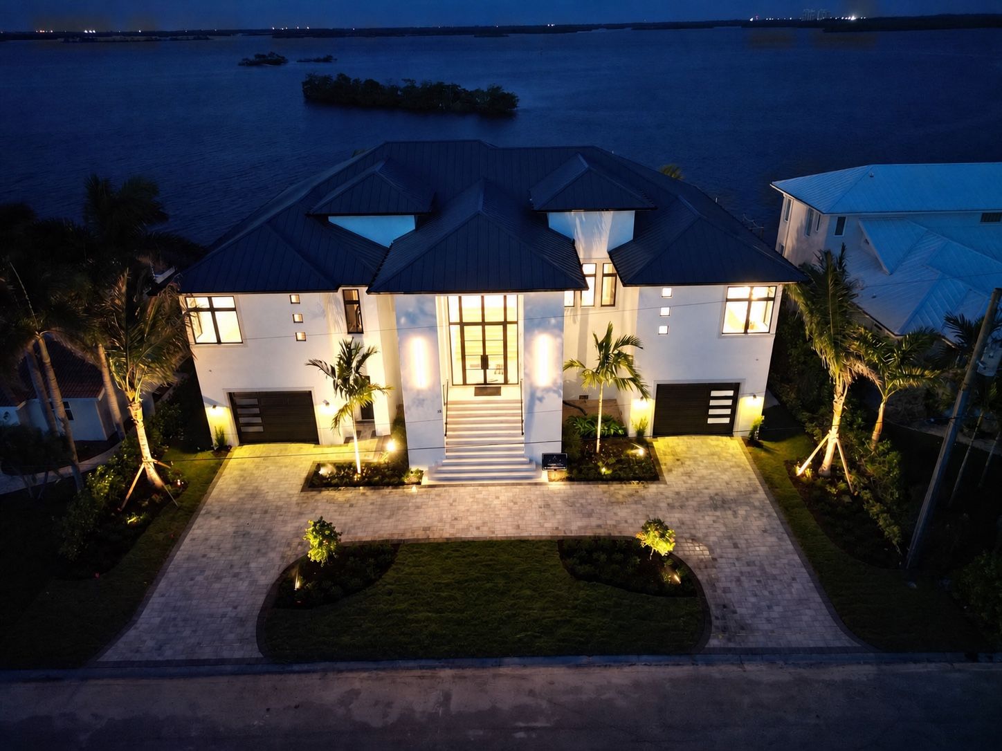 Aerial dusk view of a front entry with lighting, planting, and a clear arrival sequence