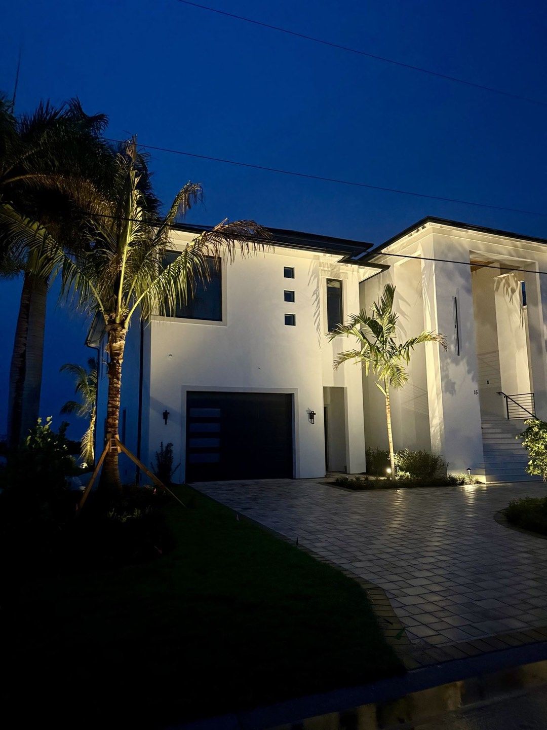 Luxury home exterior with low-voltage landscape lighting defining the entry and facade at dusk